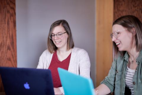 Ashley types on her computer while her coworker looks on
